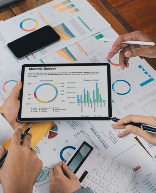 Close up business adviser partnership coworkers using a tablet to chart company financial statements report and profits work progress and planning in office room.